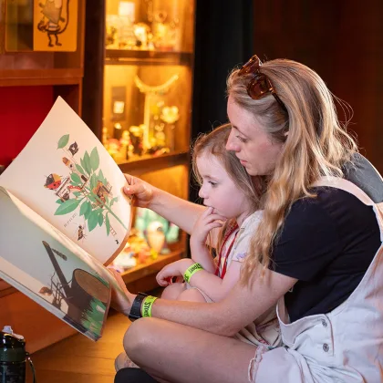Child reading book with person